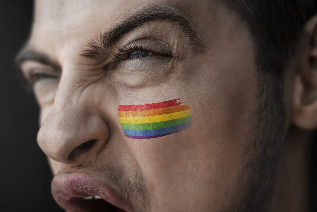 A screaming man with LGBT rainbow on face