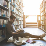 Student sitting in library with books