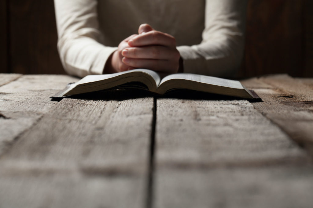 Photo of person praying with bible