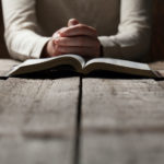 Photo of person praying with bible