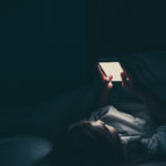Woman on phone laying in bed
