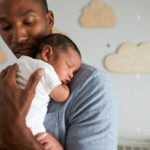 Photo of dad holding sleeping newborn baby