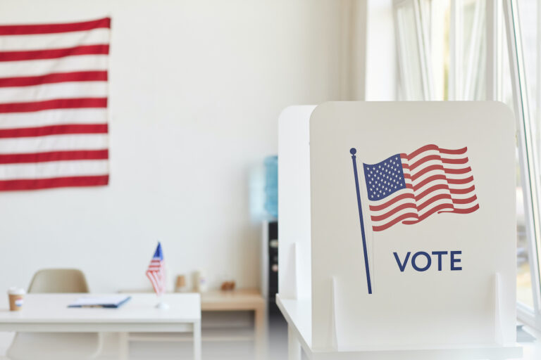 Background image of voting booths decorated with American flags at empty polling station