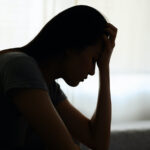 Silhouette photo of young Asian woman feeling upset, sad, unhappy or disappoint crying lonely in her room. Young people mental health care problem lifestyle concept.