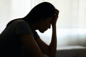 Silhouette photo of young Asian woman feeling upset, sad, unhappy or disappoint crying lonely in her room. Young people mental health care problem lifestyle concept.