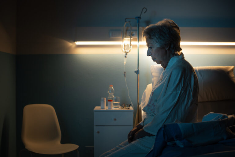 Lonely senior patient sitting on the hospital bed at night