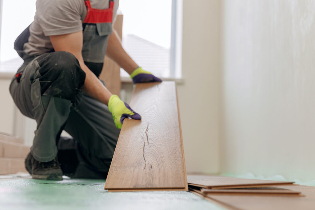 Professional builder man laying laminate flooring at home
