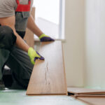 Professional builder man laying laminate flooring at home