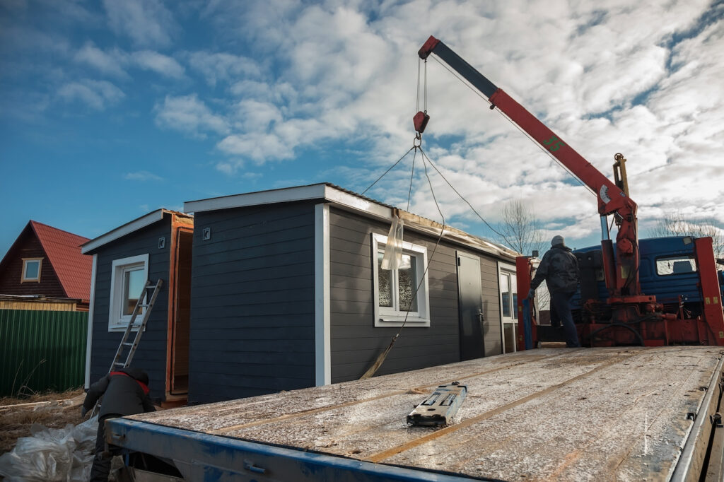 Delivery and installation of a modular frame house. Frame construction of small houses. Modular housing construction. Your house. An inexpensive house.