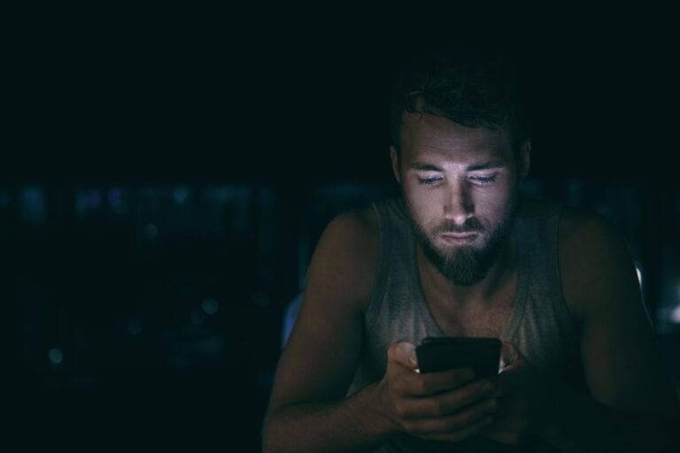 young man looking at phone in a dark room, alone