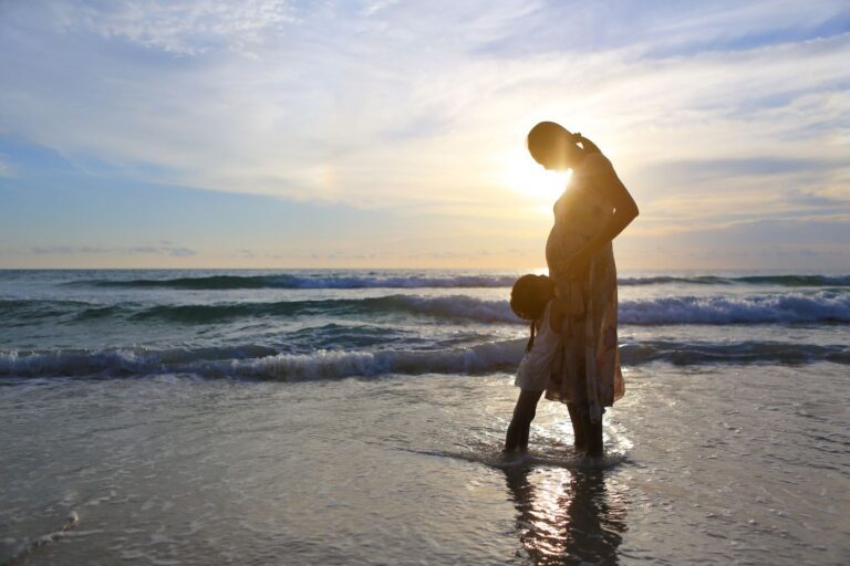 Pregnant woman and daughter on the beach